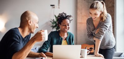 크리에이티브 오피스에서 회의 중 커피를 마시며 노트북을 바라보는 행복한 비즈니스맨들